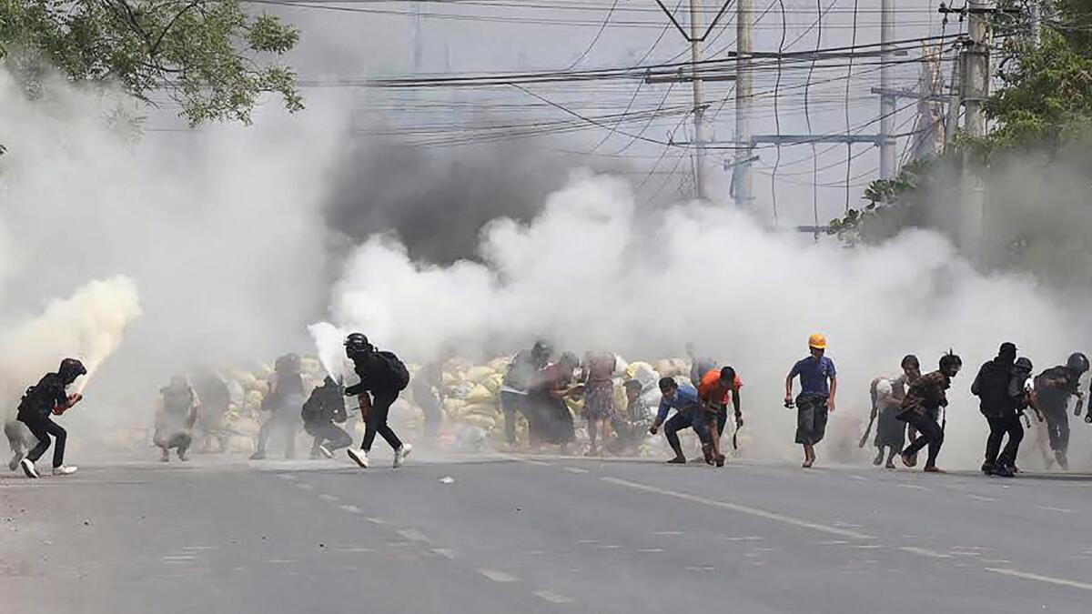 Protesters run from tear gas fired by security forces. Photo: AFP)