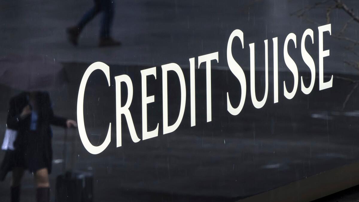 A woman walks past a logo of the Swiss bank Credit Suisse in Zurich. - AP