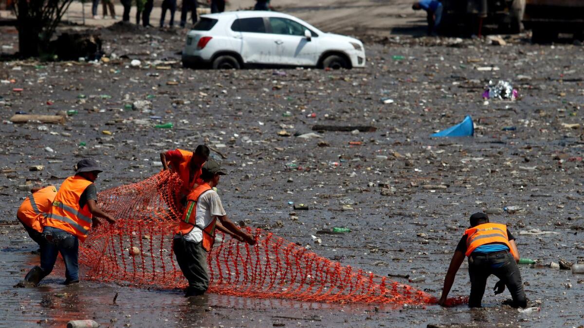 Workers try to clean a street flooded with mud after heavy rains overflowed the El Seco stream, in Zapopan, Mexico. Photo: AFP