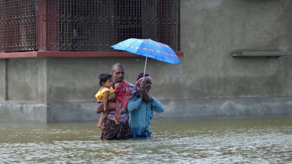 In this photograph taken on August 1, 2015, Indian villagers wade through floodwaters in Bherampur Block, Murshidabad District, some 220 km north of Kolkata.