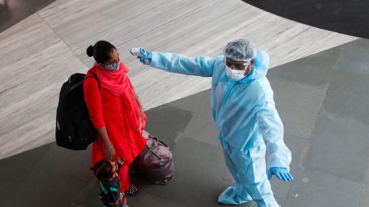 A health worker in personal protective equipment (PPE) checks the temperature of a passenger at a railway station, amid the spread of the coronavirus disease (COVID-19), in Mumbai, India November 27, 2020.