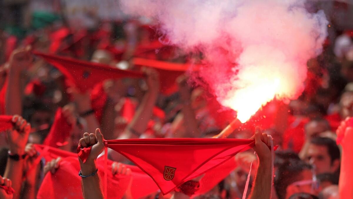 A reveller lights a flare as participants hold red scarves to celebrate the Chupinazo (start rocket) marking the kickoff at noon sharp of the San Fermin Festival.- AFP