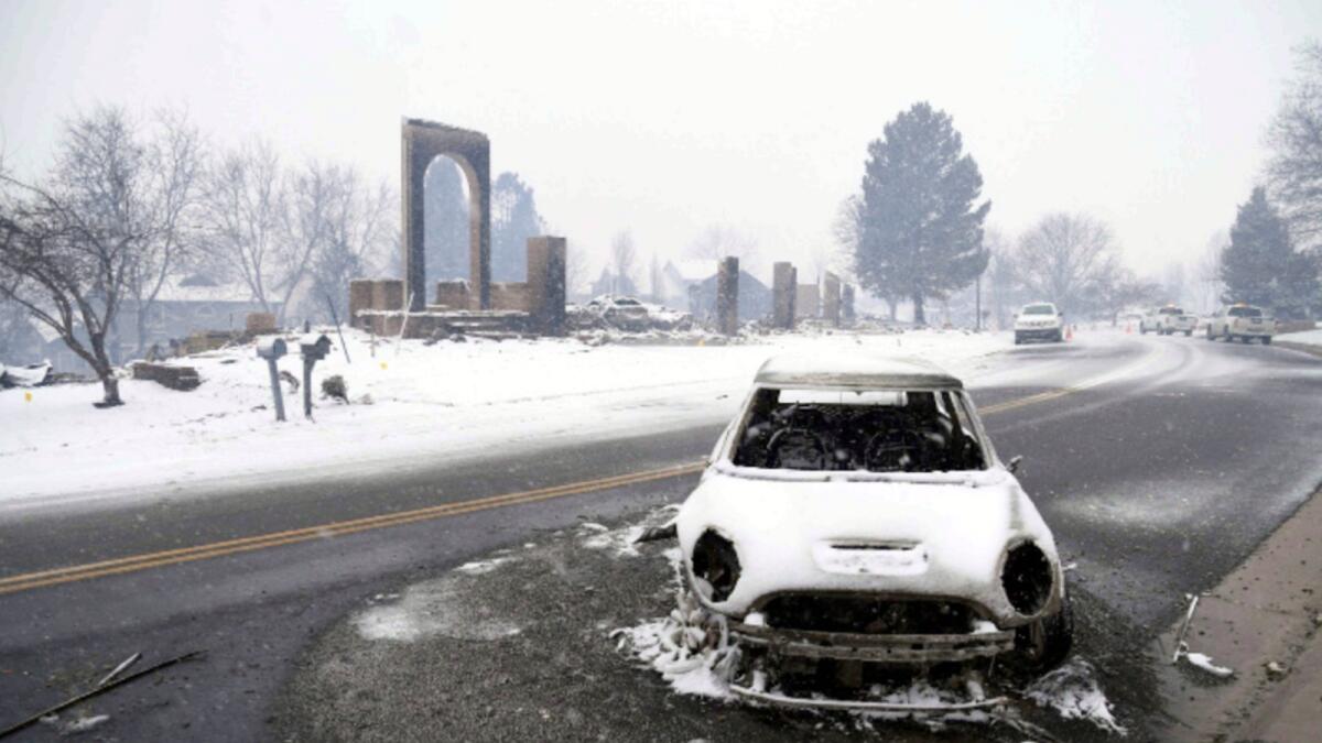 A burned out car sits in the middle of the road amidst the remnants of a wildfire in Louisville, Colorado. — AP