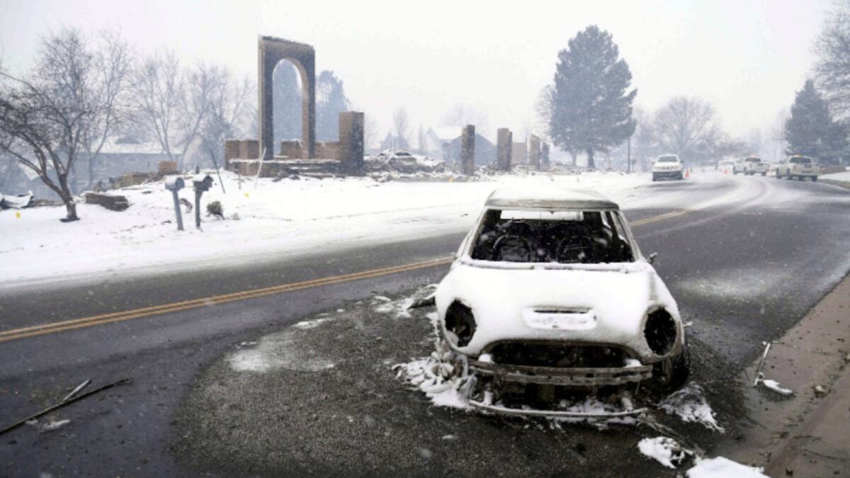 A burned out car sits in the middle of the road amidst the remnants of a wildfire in Louisville, Colorado. — AP