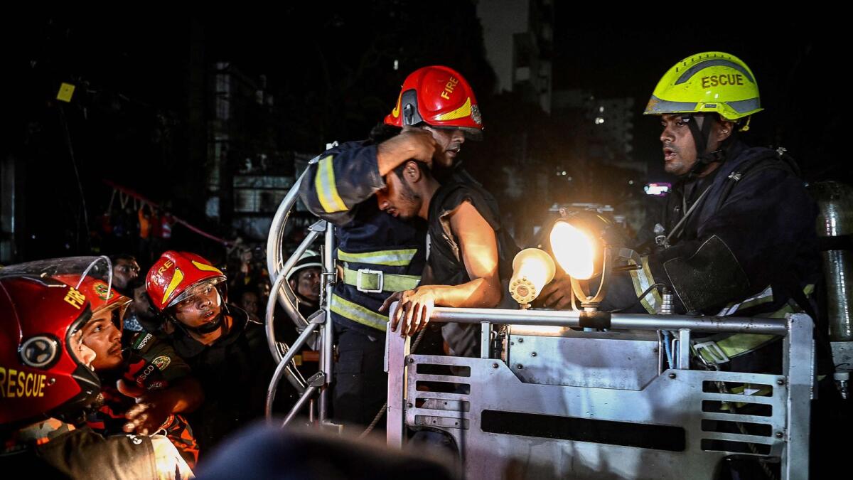 Firefighters use a fire ladder to extract victims during rescue operations following a fire in a commercial building that killed at least 43 people, in Dhaka. — AFP
