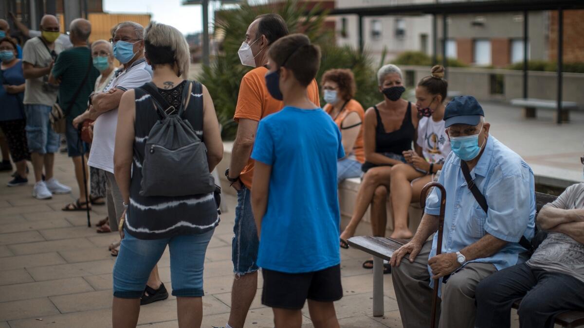 People wearing face masks wait their turn to be called for a PCR test for the Covid-19 outside a local clinic in Santa Coloma de Gramanet in Barcelona, Spain. Photo: AP