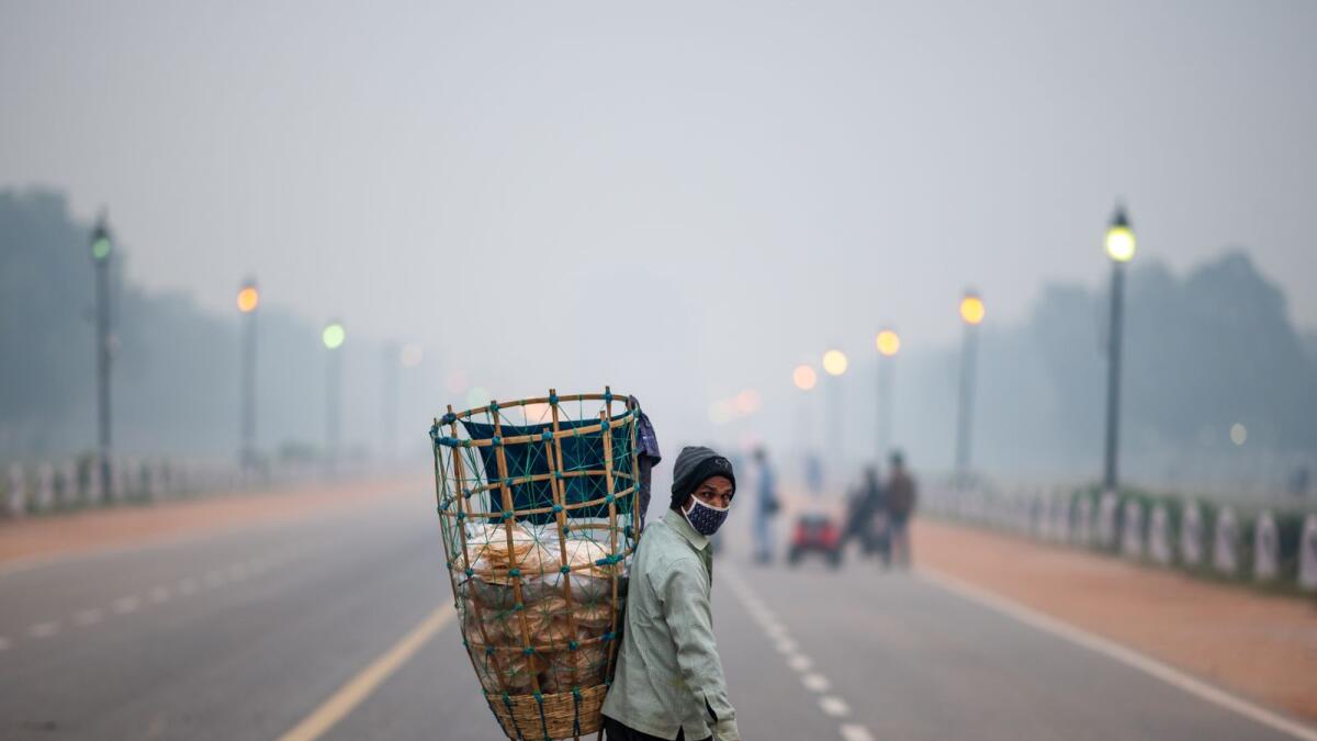 A vendor selling traditional snacks looks for customers along Rajpath street amid smoggy condition in New Delhi on November 4, 2020. (Photo by Jewel SAMAD / AFP)