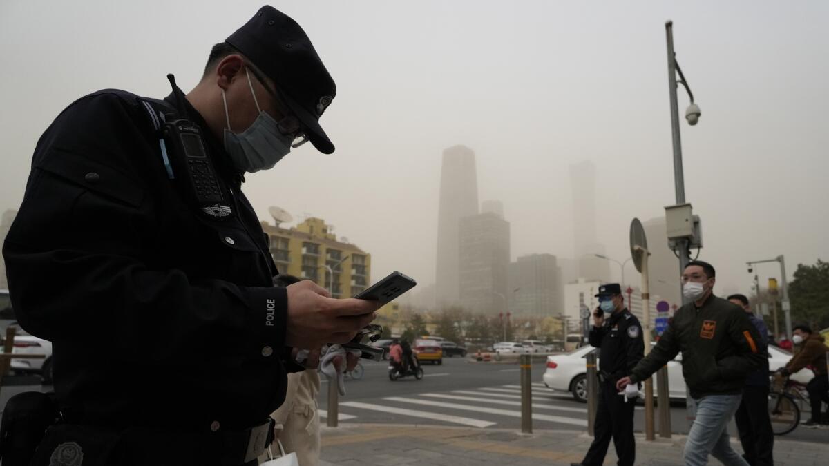 Chinese police officers monitor a junction as a dust storm sweep by in Beijing. — AP