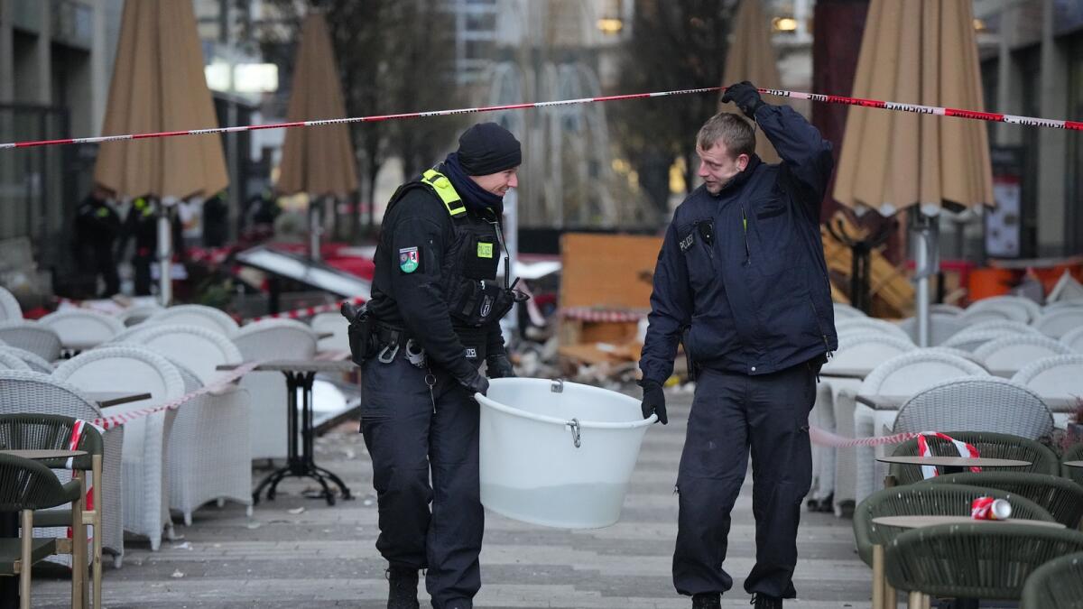 Police officers carry a plastic tub with rescued fish after a huge aquarium bursts in Berlin, Germany, on Friday. — AP