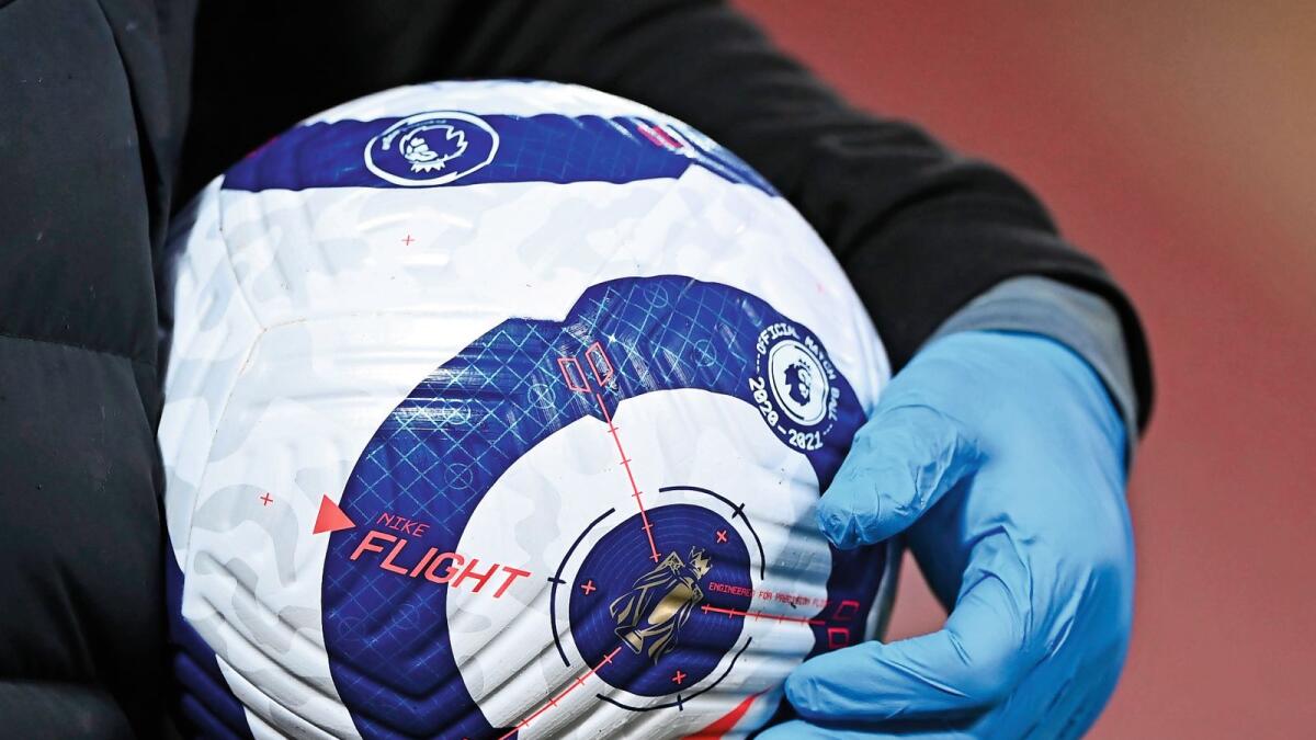 A member of the ground staff carries a ball wearing plastic gloves against the coronavirus ahead of a English Premier League game. — AP
