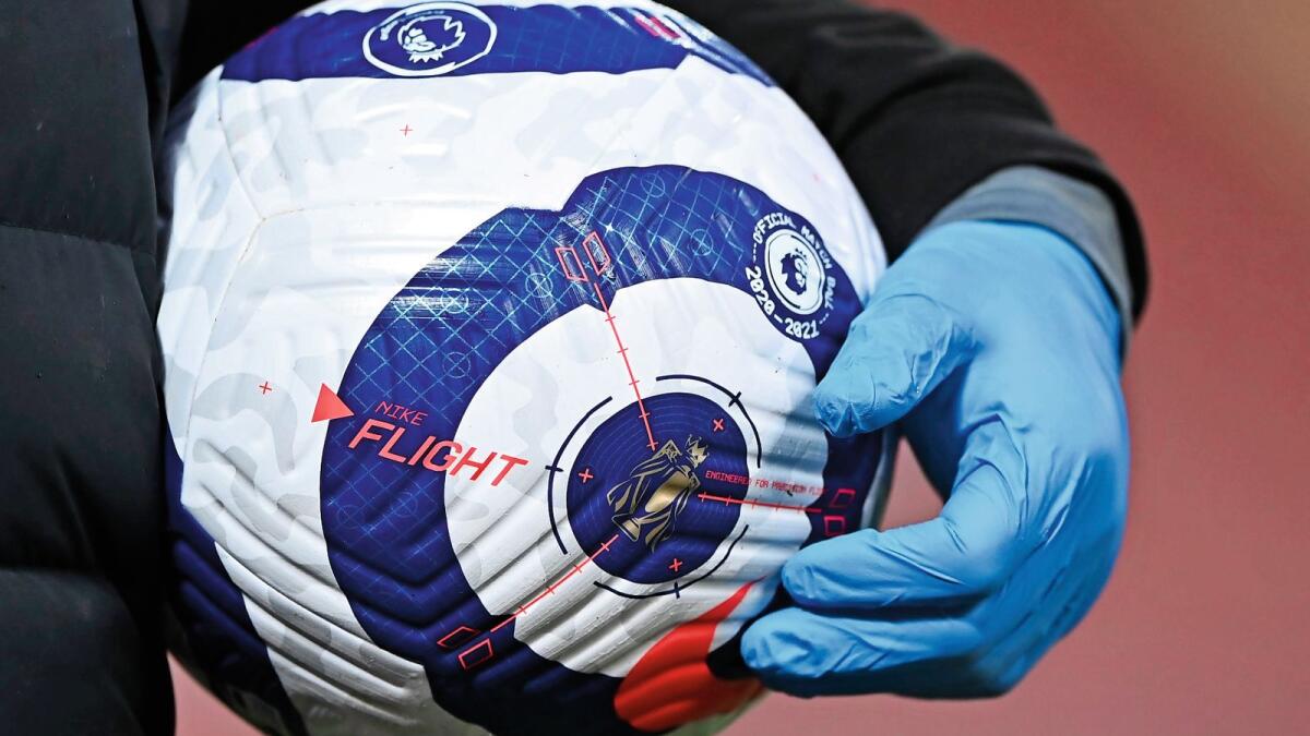 A member of the ground staff carries a ball wearing plastic gloves against the coronavirus ahead of a English Premier League game. — AP