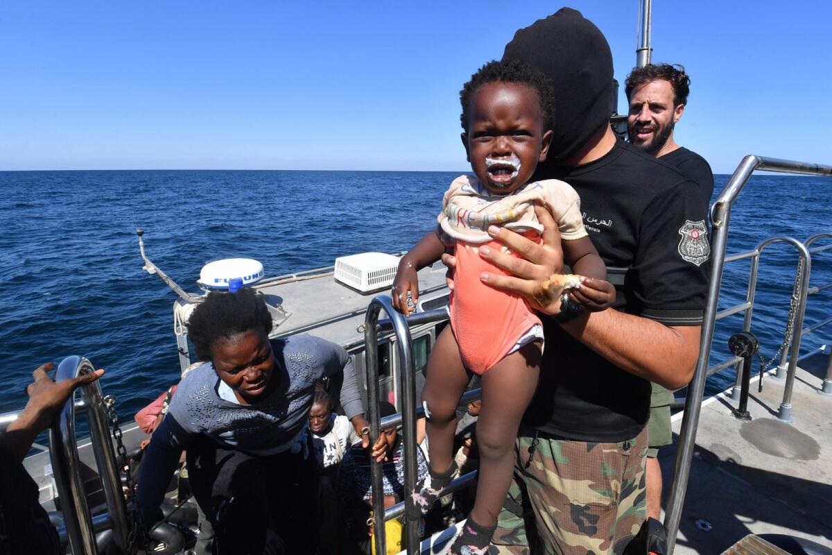 Migrants of African origin trying to flee to Europe are transferred from a small boat belonging to the Tunisian coast guard onto a larger vessel, at sea between Tunisia and Italy, on August 10, 2023.  — AFP