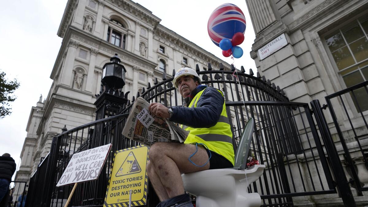 An activist sits on a toilet at the entrance to Downing Street to protest against raw sewage dumping in the rivers and seas around the UK on October 26, 2021. — AP file