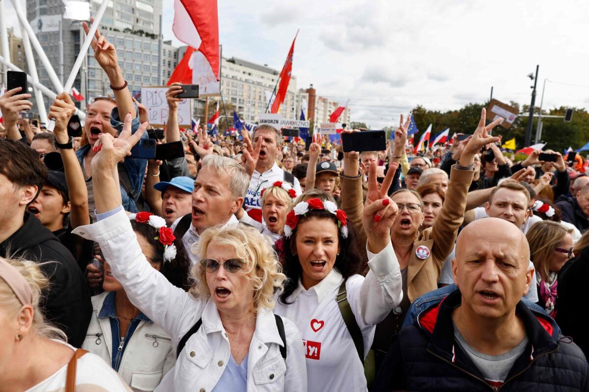 Demonstrators react as Polish opposition leader Donald Tusk (not pictured) addresses participants of a rally in Warsaw on October 1, 2023.  Polish opposition leader Donald Tusk said 'hundreds of thousands' of protesters had gathered in central Warsaw on October 1 to oppose the conservative government ahead of general elections on October 15. — AFP