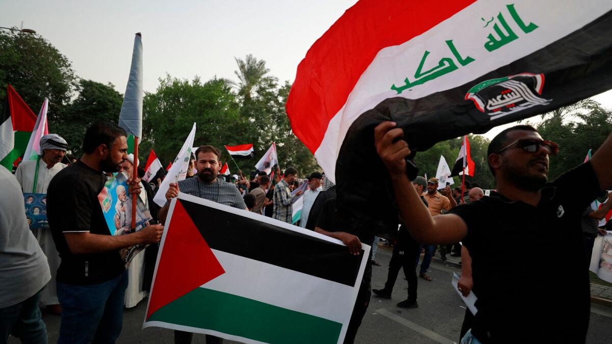 Iraqis carry placards and wave the Palestinian flag during a protest in Baghdad. — AFP