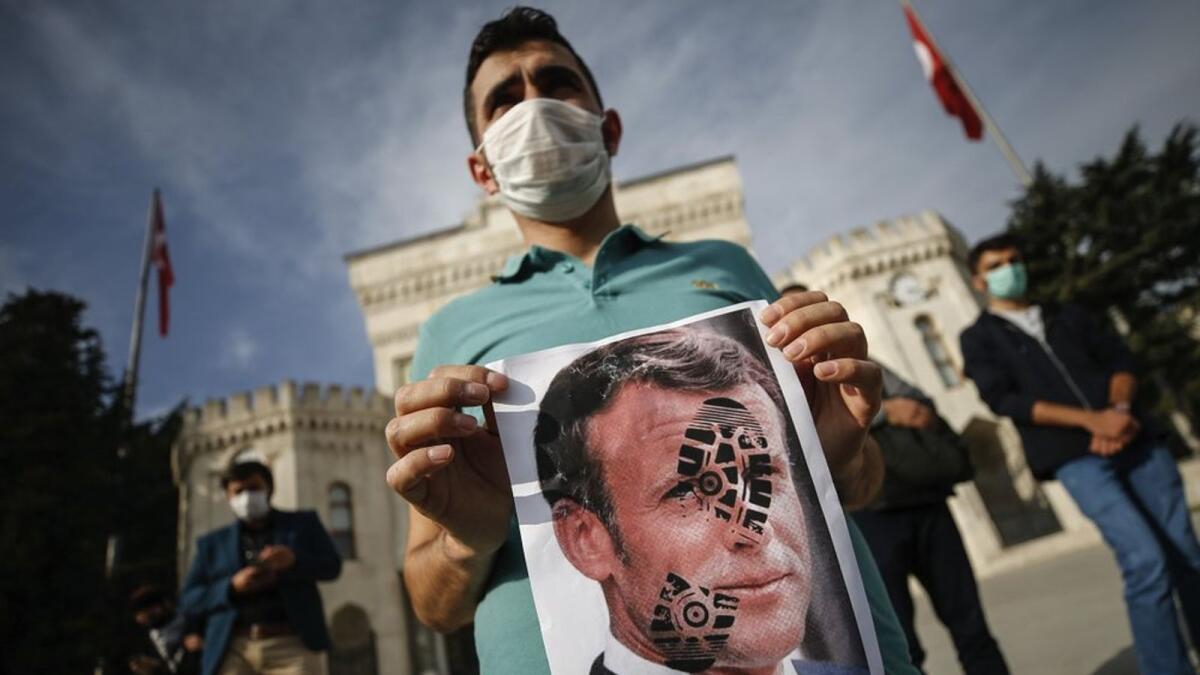 A youth holds a photograph of France's President Emmanuel Macron, stamped with a shoe mark, during a protest against France in Istanbul, Sunday, Oct. 25, 2020.
