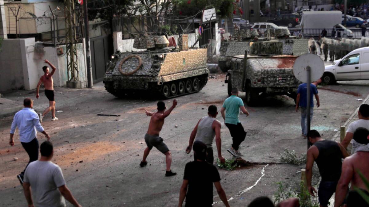 Supporters of Saad Hariri clashes with Lebanese soldiers as they throw stones against their armoured personnel carriers in Beirut. — AP