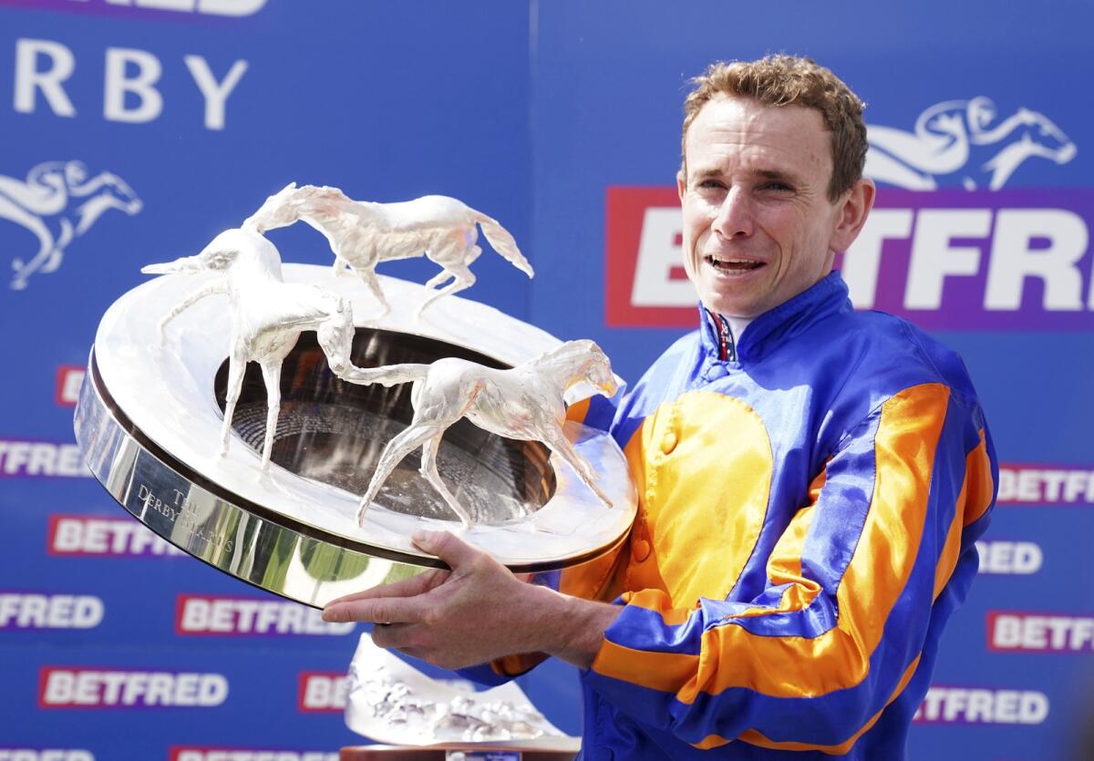 Ryan Moore holds up his third Epsom Derby trophy. - AP