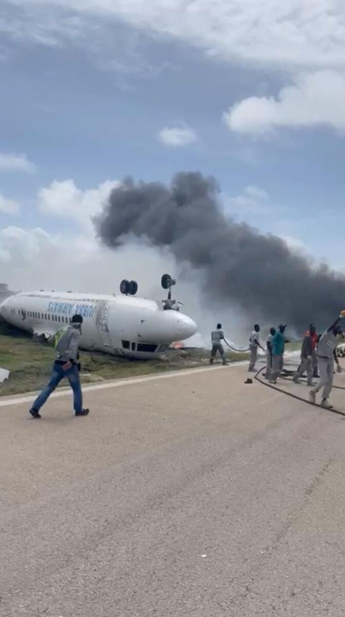 Firefighters spray water on a plane that flipped over after a crash landing, in Mogadishu, Somalia. Photo: Reuters