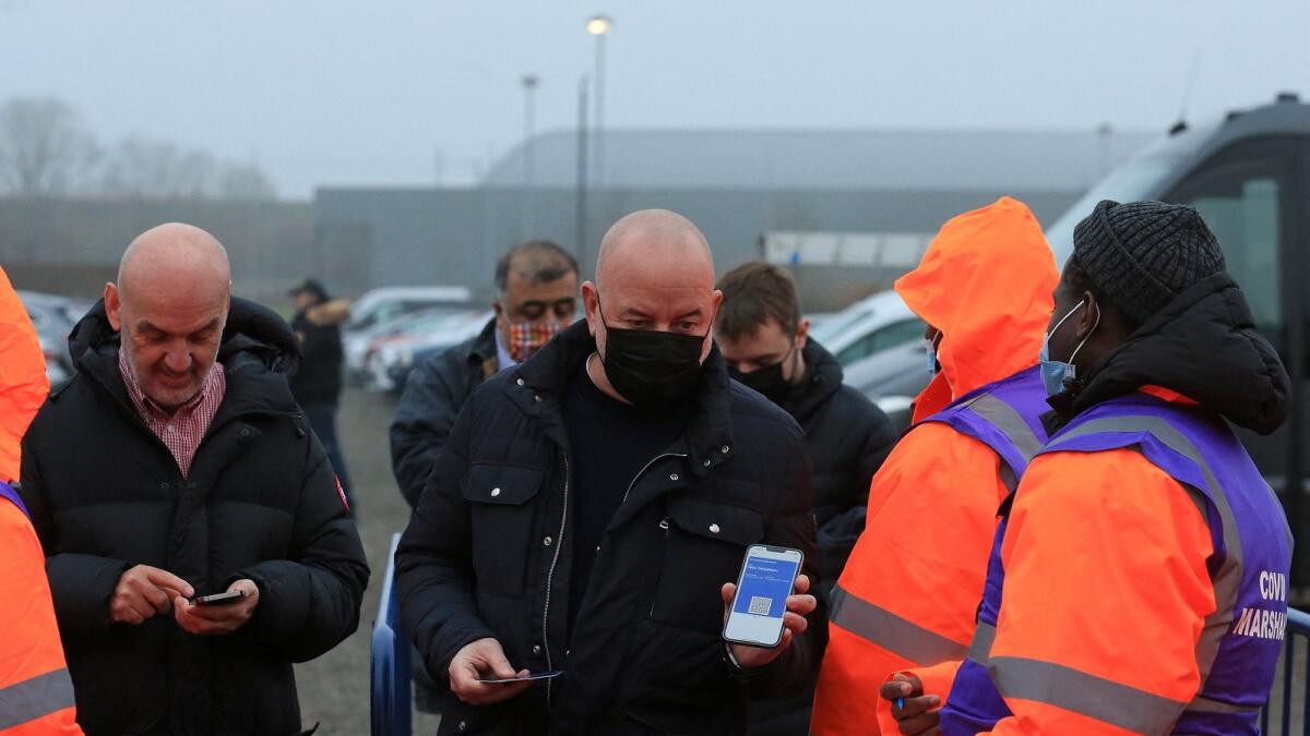 Covid-19 marshals check the status of a fan's NHS Covid Pass as they arrive to attend the English Premier League match between Leeds United and Arsenal at Elland Road. — AFP