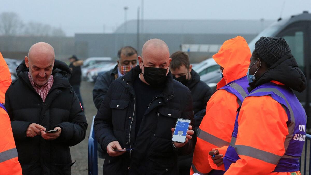 Covid-19 marshals check the status of a fan's NHS Covid Pass as they arrive to attend the English Premier League match between Leeds United and Arsenal at Elland Road. — AFP