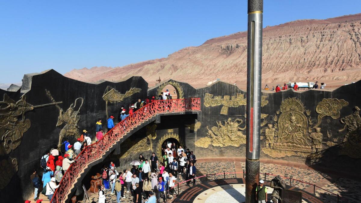 Visitors walk past a giant thermometer at a tourist site in the Flaming Mountains in Turpan in China's northwest Xinjiang region.  The area is known as one of the hottest places in China. — AFP file