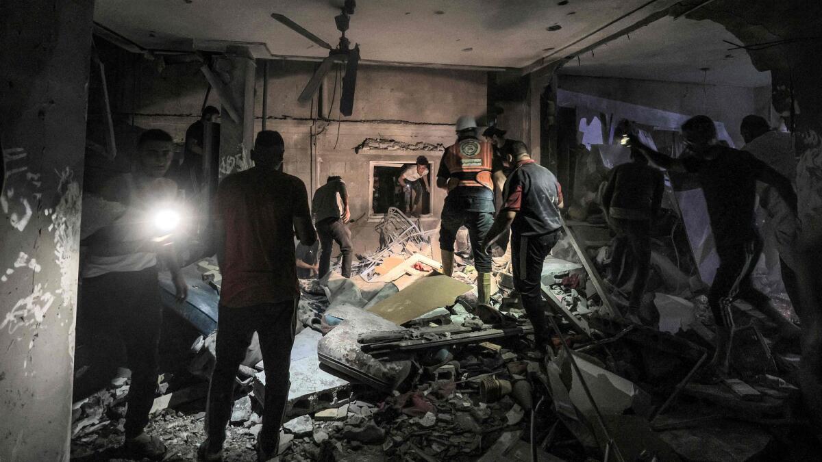 Rescuers search the home of Palestine TV journalist Mohamed Abu Hatab, who was killed along with family members during Israeli bombardment on Khan Yunis. AFP