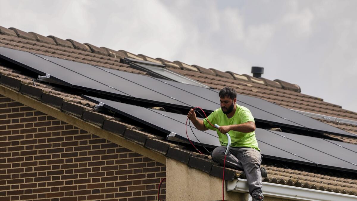 Workers instal solar planers on the roof of a house in Rivas Vaciamadrid, Spain. — AP
