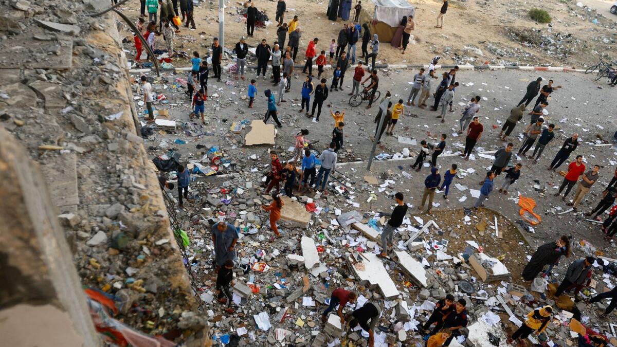 People walk among debris at the site of an Israeli strike on the apartment building in Khan Younis in the southern Gaza Strip. — Reuters
