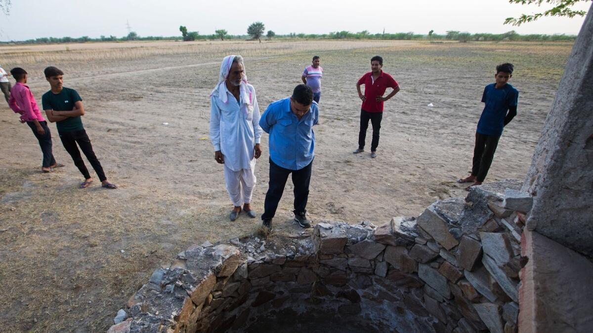 Farmer Sardar Meena (center L) stands next to the well where his three married daughters and two grandchildren were found dead. Photo: AFP