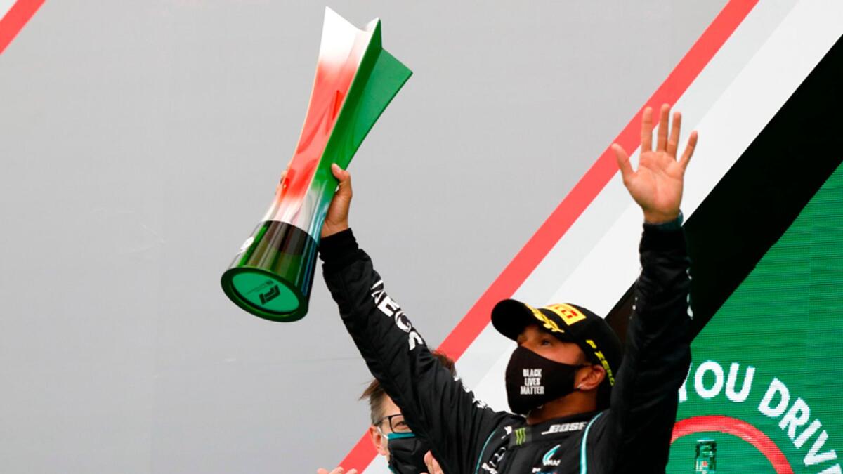 Mercedes' Lewis Hamilton celebrates on the podium with the trophy after winning the Portuguese Formula One Grand Prix. — AFP