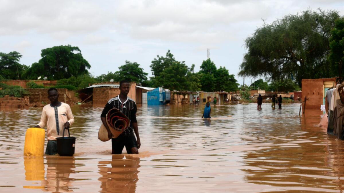 People carry their belongings while walking in a street flooded by the waters from the Niger river that flooded in the Kirkissoye neighbourhood in Niamey. Photo: AFP