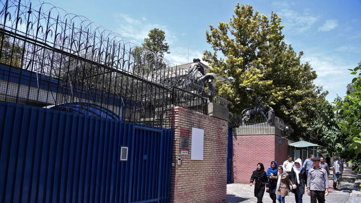 Iranian pedestrians walk past the main gate of British Embassy in Tehran, Iran.