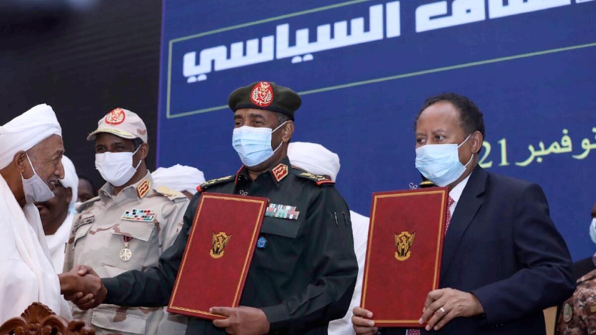 Sudan's top general Abdel Fattah Al Burhan and Prime Minister Abdalla Hamdok hold documents during a ceremony to reinstate Hamdok, who was deposed in a coup last month. — AP