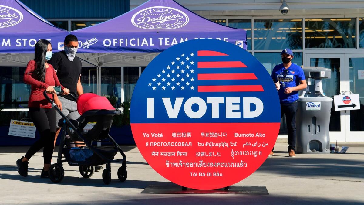 People walk past a large 'I Voted' display as early voting for the election begins at Dodger Stadium in Los Angeles, California. AFP