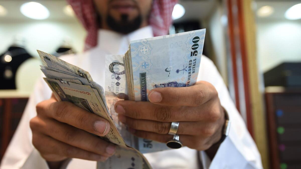 A man counts Saudi riyal banknotes at his jewellery shop in Tiba market in the Riyadh. — AFP file photo