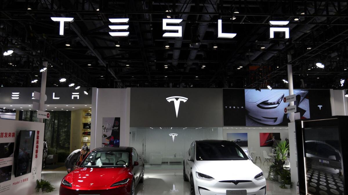 A staff member looks at Tesla's new Model 3 sedan displayed next to Model X SUV. — Reuters