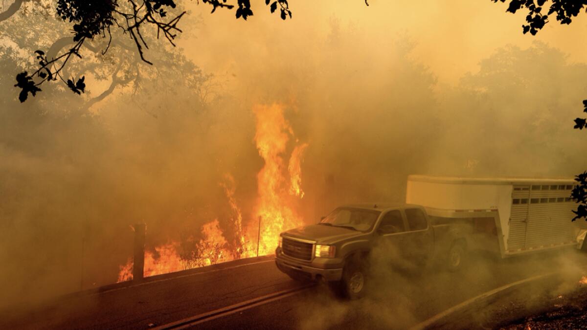 A livestock trailer drives along Canada Road as the Crews Fire burns near Gilroy, California, on Sunday, July 5, 2020. AP
