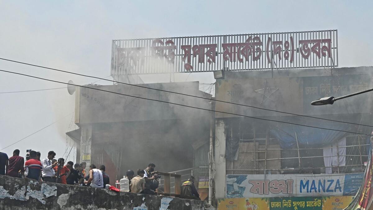 Firefighters extinguish the fire after it broke out at a market in Dhaka on Saturday. — AFP