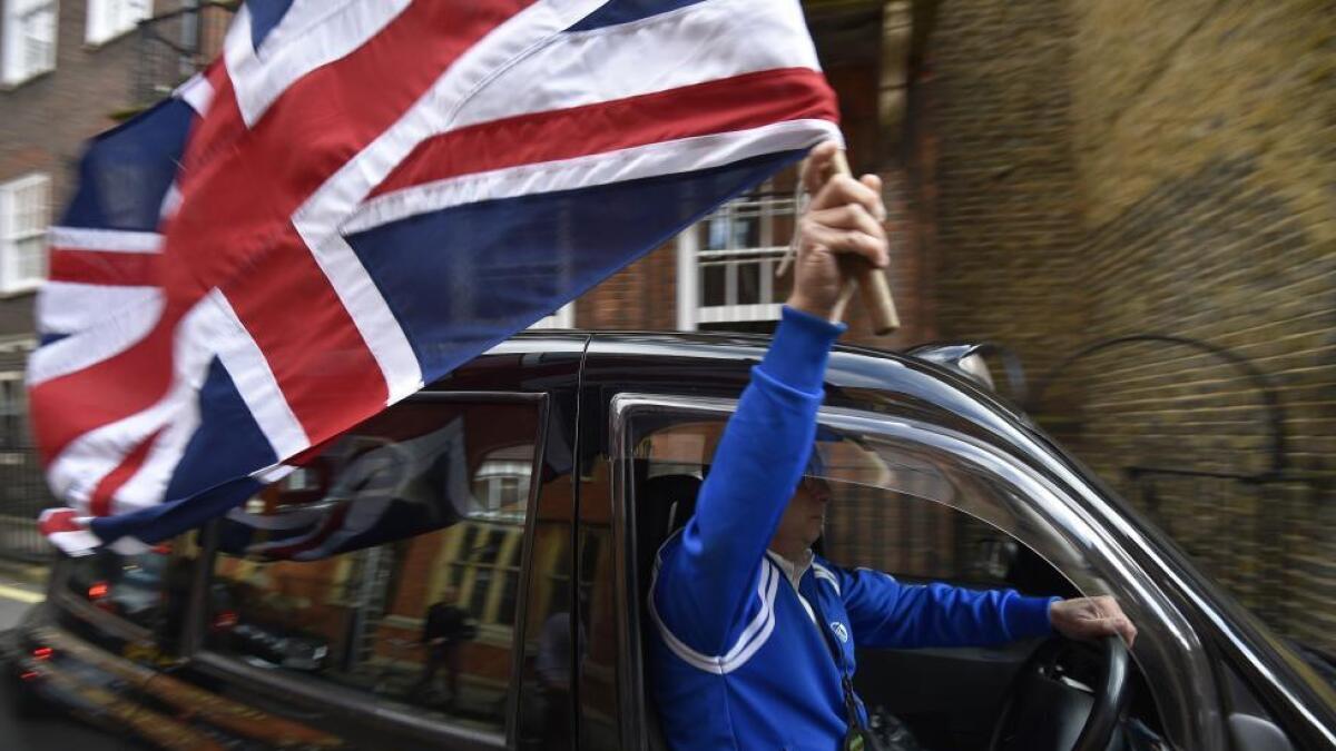 A taxi driver holds a Union flag, as he celebrates following the result of the EU referendum, in central London, Britain June 24, 2016