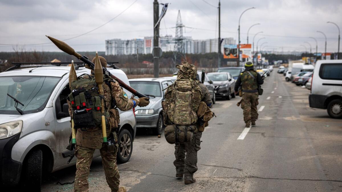 Ukrainian servicemen carry rocket-propelled grenades and sniper rifles as they walk towards the city of Irpin, northwest of Kyiv, on March 13, 2022. Photo: AFP