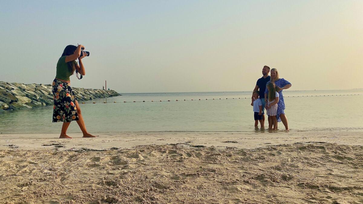 Paula Hainey, a photographer, gives a free family photo session at a beach to a family leaving Dubai for the UK, in Dubai. Photo: Reuters