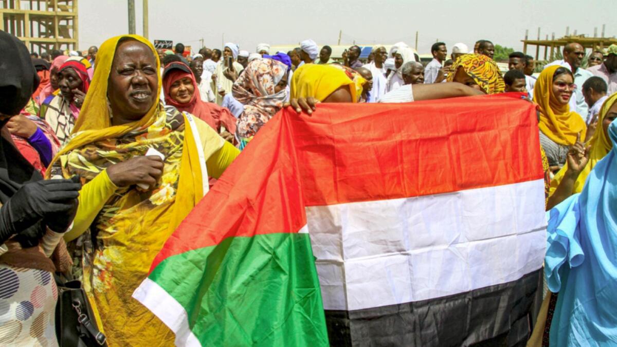 Women hold up a Sudanese national flag during a protest in Sudan's capital Khartoum. — AFP