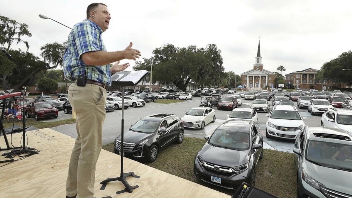 Pastor Cliff Lea preaches over a parking lot filled with cars during a drive-in service at the First Baptist Church of Leesburg on Easter Sunday. Photo: AP