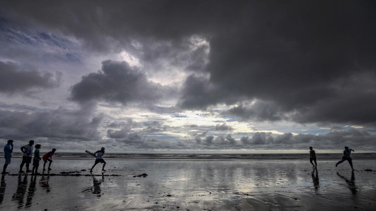 Children play cricket as dark clouds gather in the sky over Juhu beach in Mumbai, India. Photo: PTI