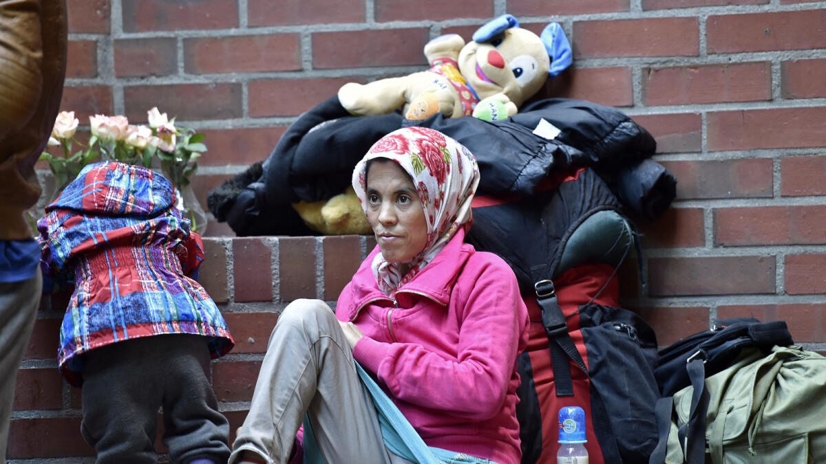 A woman rests on a wall as migrants arrive in Dortmund, Germany, Sunday, Sept. 6, 2015. Thousands of migrants and refugees came to Dortmund by trains. (AP Photo)