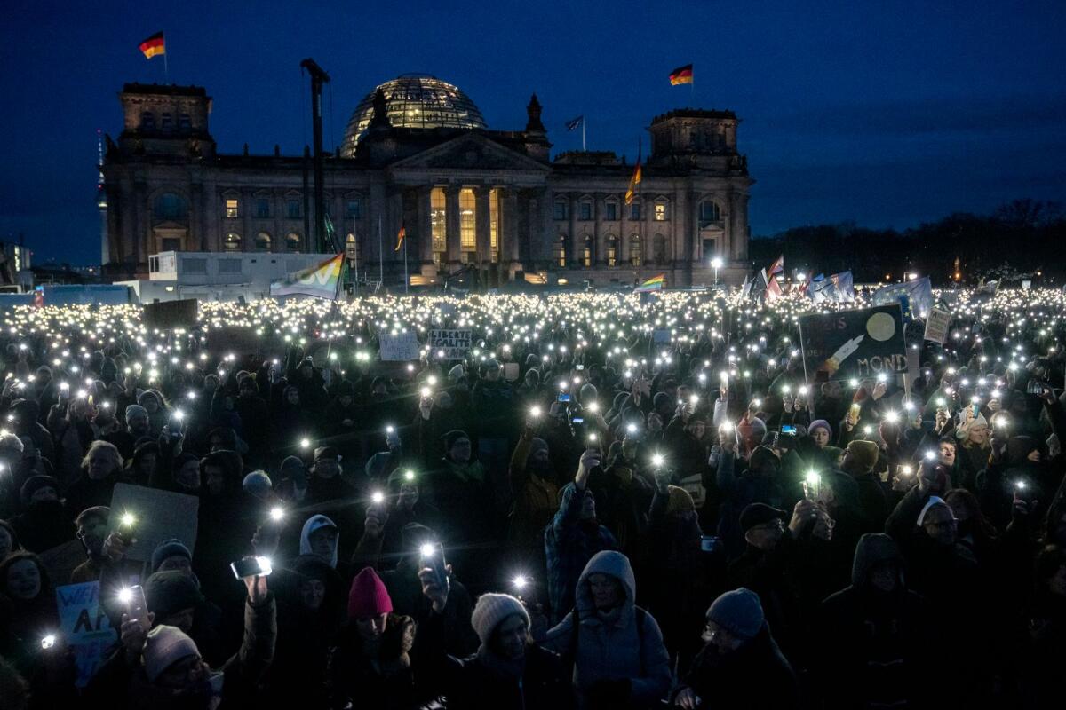 People hold up their cell phones as they protest against the AfD party and right-wing extremism in front of the Reichstag building in Berlin, Germany, on Jan. 21, 2024. — AP