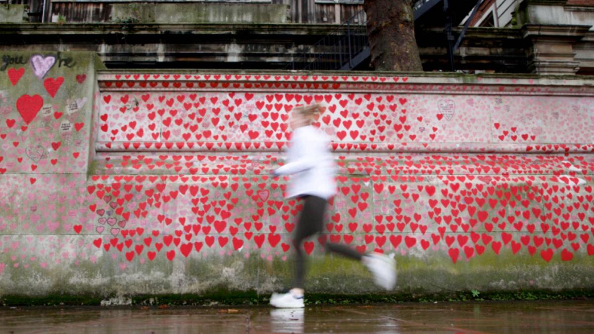 A woman jogs alongside the National Covid Memorial Wall in London. — AP