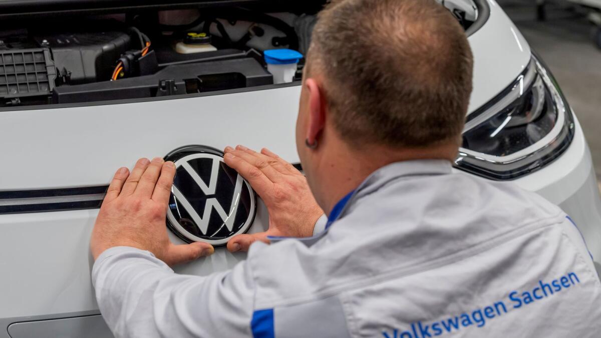 An employee fixes a VW sign at a production line of the electric Volkswagen model ID.3 in Zwickau, Germany. — Reuters