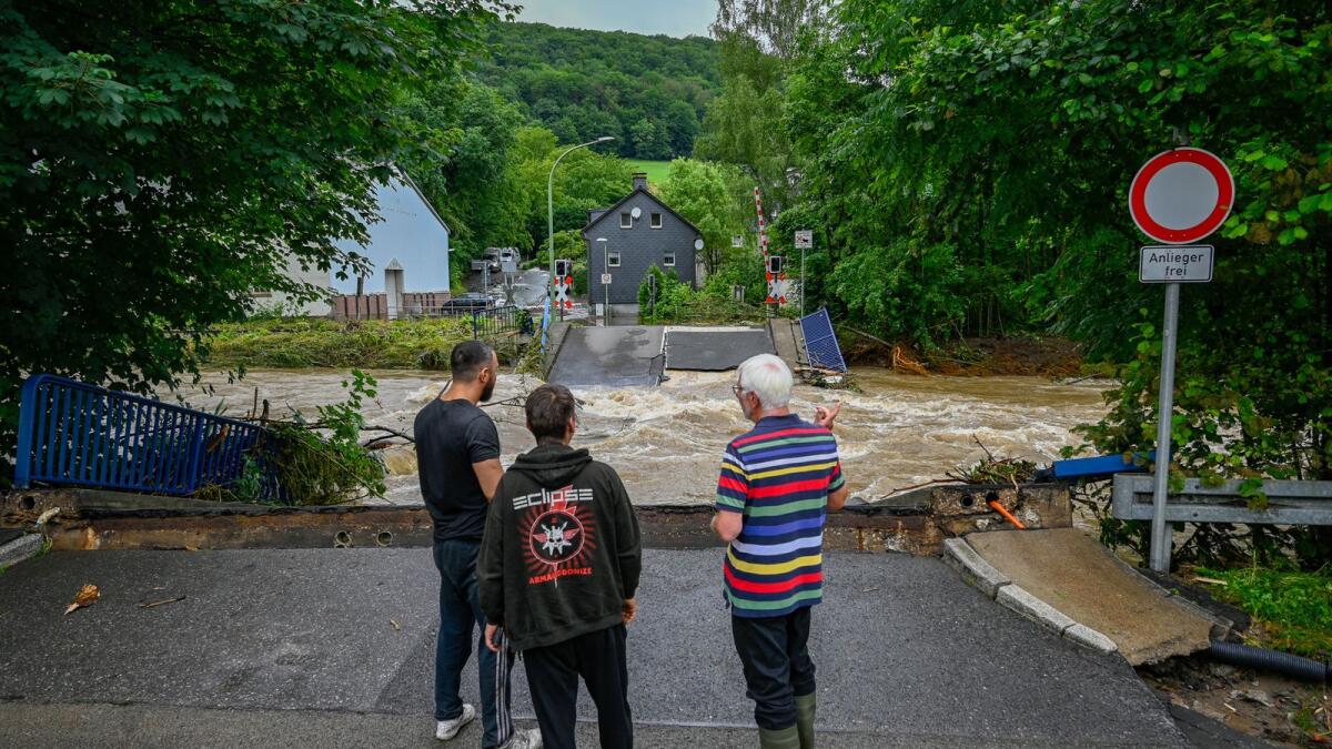 People look at a destroyed railway crossing and damagescaused by the floods in western Germany. Photo: AFP